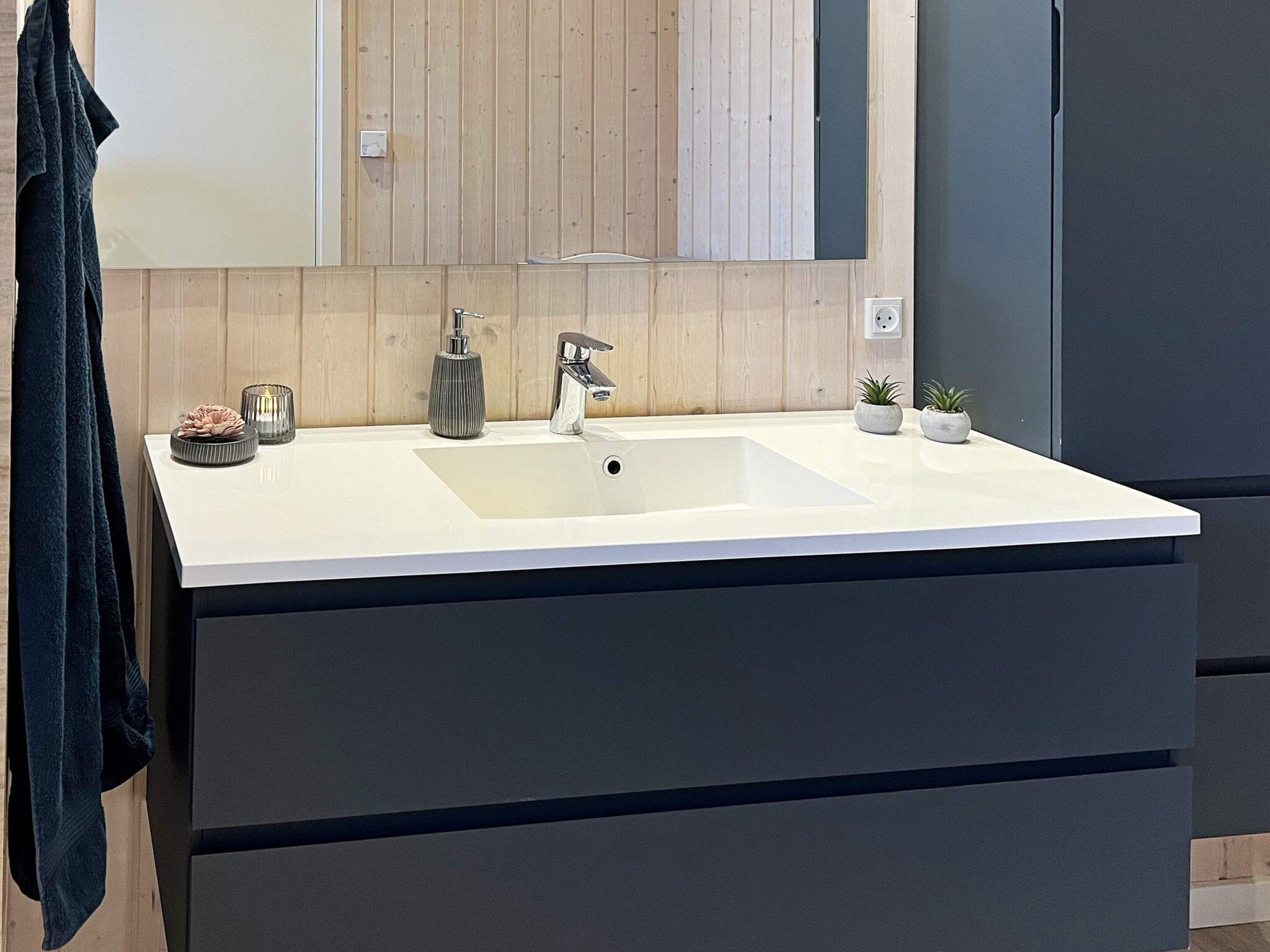 Une salle de bain moderne avec un lavabo blanc, un miroir et un lambris en bois.