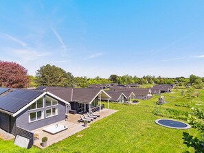 A residential area with multiple houses featuring solar panels, a grassy lawn, and a clear sky. - 5 Star Holiday Home in Vejby (Vejby)