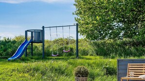 Un bain à remous dans un jardin, avec un toboggan et des balançoires.