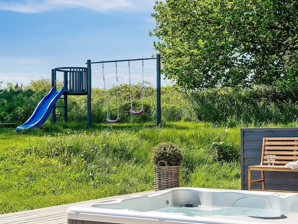 A hot tub in a garden with a slide and swings. - 5 Star Holiday Home in Vejby (Vejby)