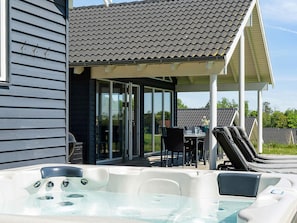 A hot tub area with a covered patio, a table, and chairs.