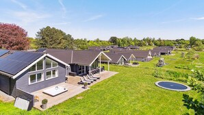 Une rangée de maisons modernes de plain-pied, dotées de panneaux solaires, d’une pelouse et d’une piscine.
