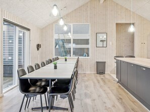 A modern kitchen with a long dining table, black chairs, and pendant lighting. - 5 Star Holiday Home in Vejby (Vejby)