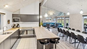 Une cuisine spacieuse dotée d’un îlot central, d’appareils électroménagers modernes et d’un coin repas avec une longue table et des chaises.