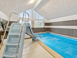 An indoor swimming pool with a slide, a ladder, and a view of the outside. - 5 Star Holiday Home in Vejby (Vejby)