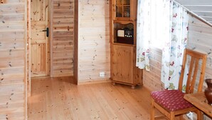 A wooden interior with a wooden cabinet, a chair with a patterned cushion, and a window with floral curtains. - 4 Person Holiday Home in Gurskoy (Heroy)