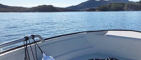 A boat's interior with a view of calm water and distant hills.