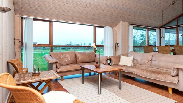 A spacious living room with a large window, a sofa, a coffee table, and wicker chairs. - 6 Person Holiday Home in Tarm-by Traum (Tarm)