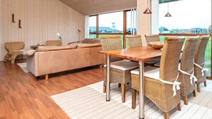 A spacious room with a wooden ceiling, a sofa, wicker chairs, a dining table, and large windows offering a view of the outdoors. - 6 Person Holiday Home in Tarm-by Traum (Tarm)