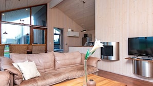 A modern living room with a beige sofa, a wooden coffee table, and a vase with flowers. - 6 Person Holiday Home in Tarm-by Traum (Tarm)
