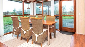 A dining area with wicker chairs and a wooden table, large windows, and a view of the outdoors. - 6 Person Holiday Home in Tarm-by Traum (Tarm)