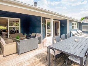 A covered outdoor area with a dining table, chairs, and lounge chairs. - 4 Star Holiday Home in Glesborg (Glesborg)