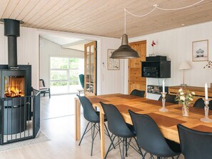 A modern interior with a central fireplace, dining area, and a television. - 4 Star Holiday Home in Glesborg (Glesborg)