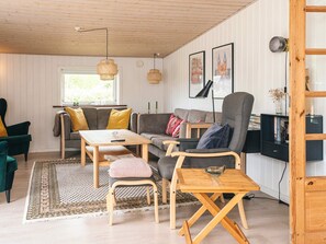 A cozy living room with a sofa, armchairs, a coffee table, and a bookshelf. - 4 Star Holiday Home in Glesborg (Glesborg)