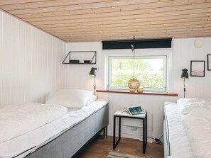 A bedroom with two single beds, a small table, a window with a view, and two wall-mounted lamps. - 4 Star Holiday Home in Glesborg (Glesborg)