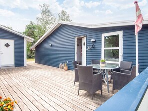 A blue building with a deck, a table with chairs, and a flag. - 4 Star Holiday Home in Glesborg (Glesborg)
