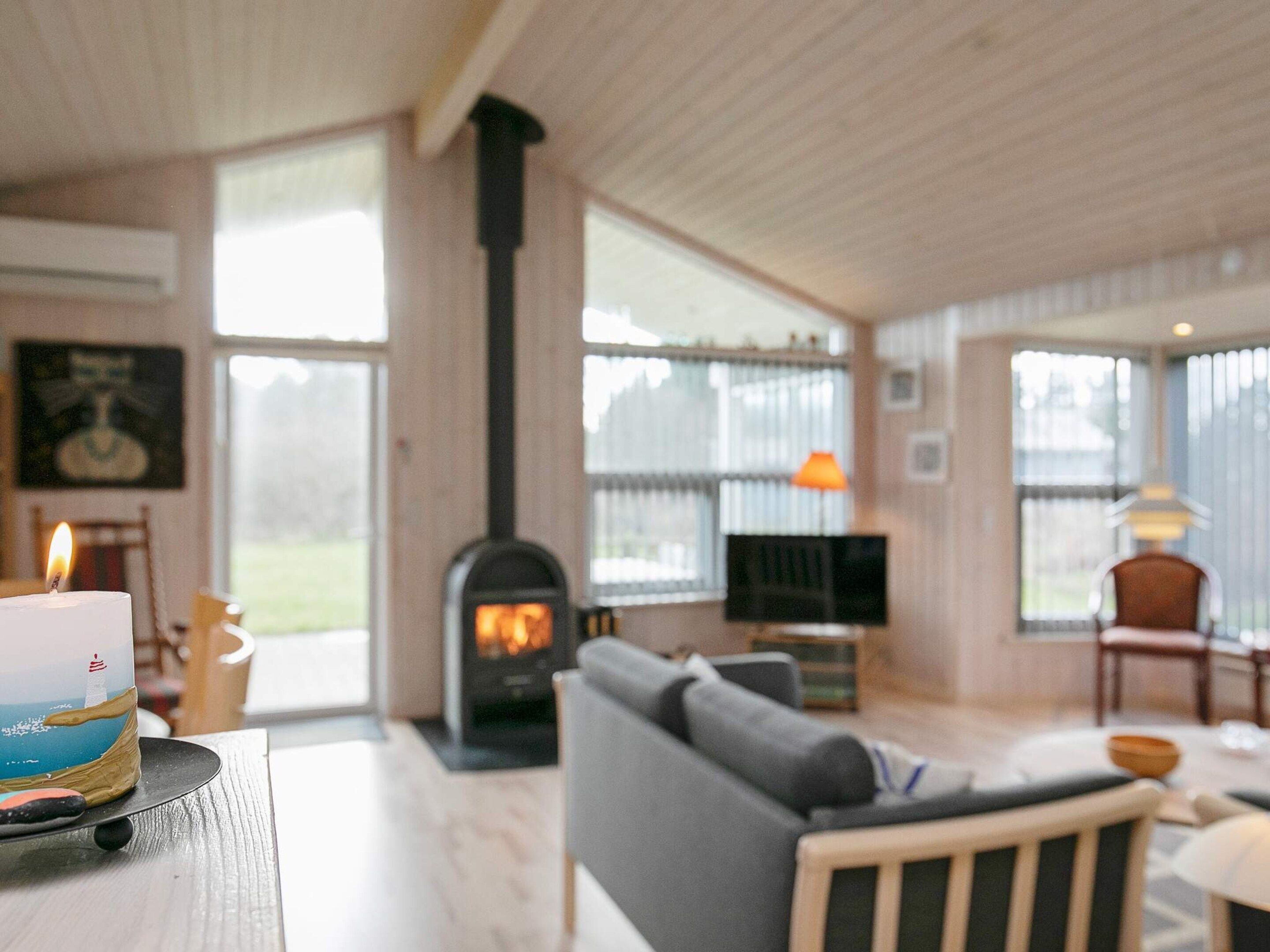 A living room with a fireplace, a sofa, a television, and a table with a candle.