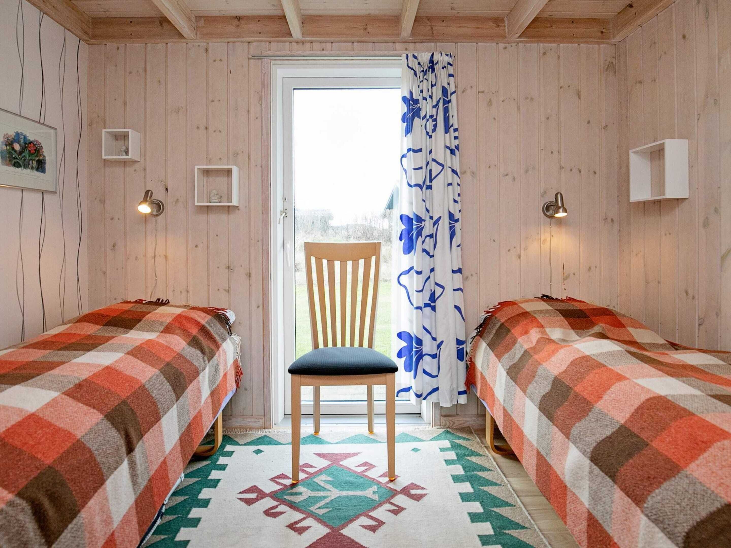 Una habitación acogedora con dos camas, una silla y un tapete estampado.