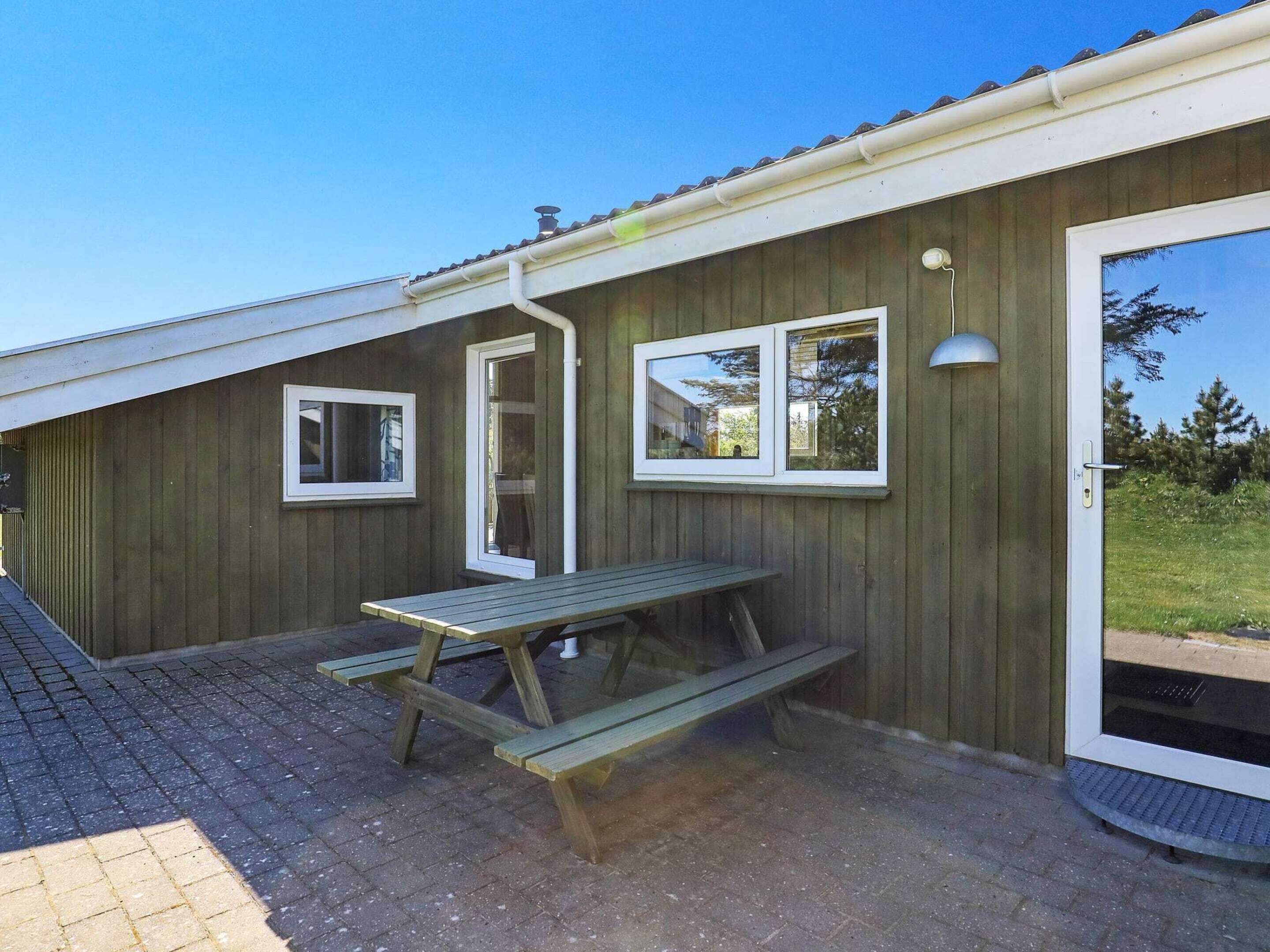 Un bâtiment en bois avec une table de pique-nique et deux fenêtres.
