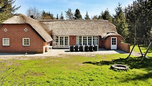 A thatched-roof building with a brick exterior, large windows, and a paved area in front. - 12 Person Holiday Home in Ulfborg (Ulfborg)
