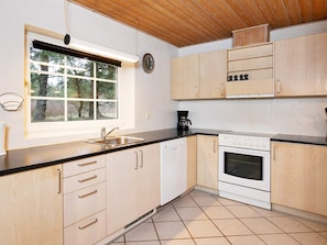 A kitchen with wooden cabinets, a sink, a stove, and a window with blinds. - 12 Person Holiday Home in Ulfborg (Ulfborg)