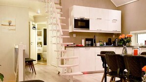 A modern kitchen with white cabinets, a microwave, and a dining area with a table and chairs. - Holiday Home in BrattvÃ¥g (Ålesund)