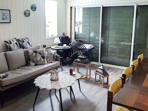 A living room with a sofa, a coffee table, a dining table with chairs, and a sliding glass door leading to an outdoor area. - Holiday Home in BrattvÃ¥g (Ålesund)