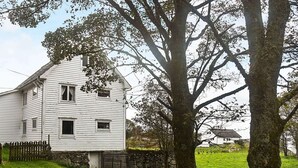 Ein weißes, zweistöckiges Haus mit Stein Fundament, umgeben von einer Stein Mauer und einem Holzzaun.