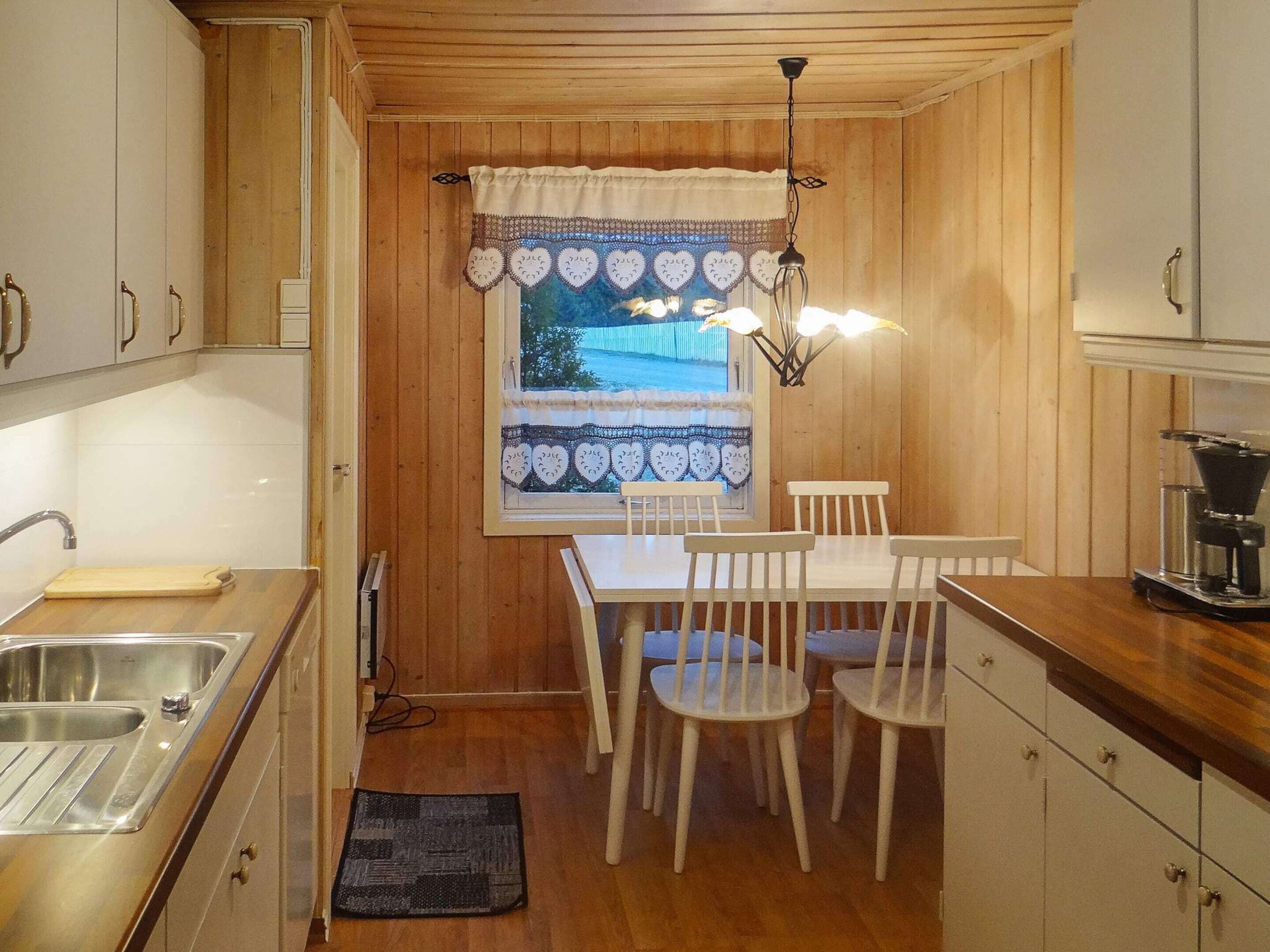 A compact kitchen with a dining table, chairs, a coffee machine, and a window with a view.