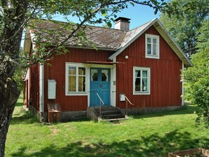 A red wooden house with a blue door, white windows, and a small porch. - 5 Person Holiday Home in Kalvsvik (Kalvsvik)