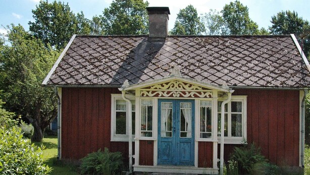 A small red house with a blue door and white trim, surrounded by greenery. - 5 Person Holiday Home in Kalvsvik (Kalvsvik)