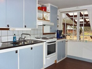 A compact kitchen with a sink, stove, and cabinets. - 5 Person Holiday Home in Kalvsvik (Kalvsvik)