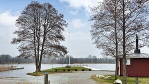 A gravel path leading to a dock by a lake, with a red building and a flagpole in the background. - 5 Person Holiday Home in Kalvsvik (Kalvsvik)