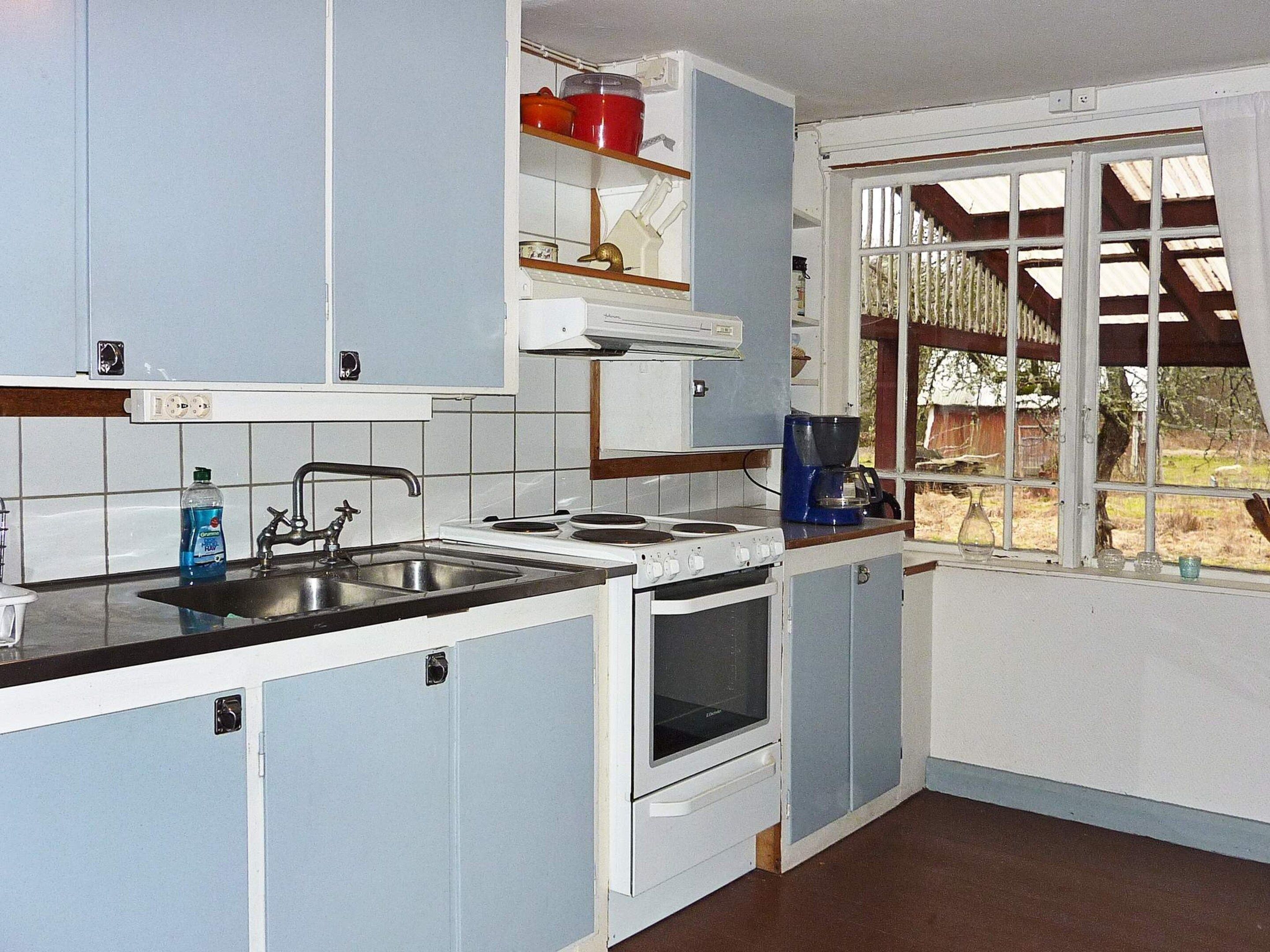 A compact kitchen with a sink, stove, and coffee maker.
