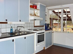 A compact kitchen with a sink, stove, and coffee maker. - 5 Person Holiday Home in Kalvsvik (Kalvsvik)