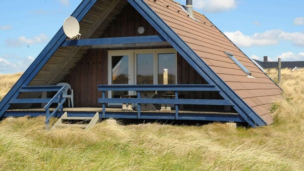 A triangular wooden cabin with a glass door, a chimney, and a satellite dish.