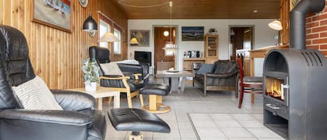 A cozy living room with leather sofas, a fireplace, and wooden walls.