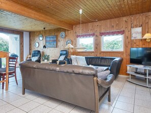 Un salon confortable avec un canapé en cuir, un téléviseur et un coin repas comprenant une table et des chaises.