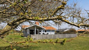 Et etplanshus med veranda, omgivet af et træhegn og en græsplæne.