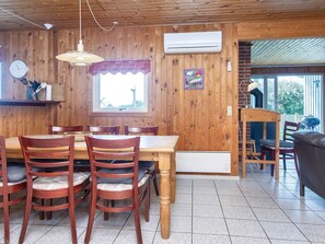 Un intérieur en bois comprenant une table à manger, des chaises, une horloge et un appareil de climatisation.