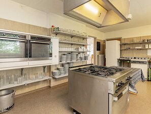 A kitchen with stainless steel appliances, including a stove and oven, and shelves with plates and glasses. - 40 Person Holiday Home in Hurup Thy (Hurup Thy)