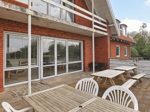 A brick building with large windows and a covered patio area with wooden tables and chairs. - 40 Person Holiday Home in Hurup Thy (Hurup Thy)