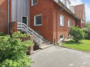 A red brick building with a white staircase leading to a door, surrounded by greenery. - 40 Person Holiday Home in Hurup Thy (Hurup Thy)