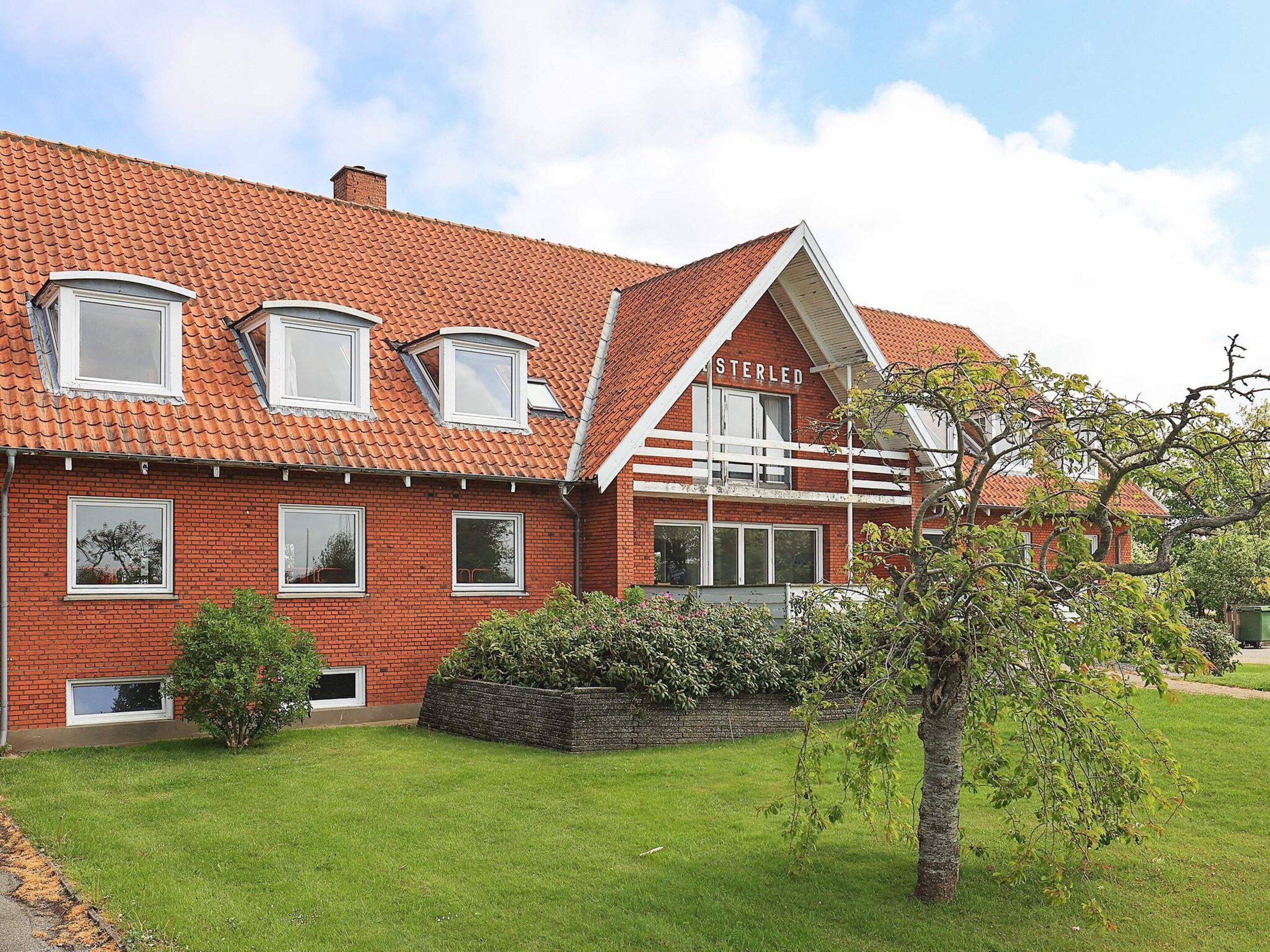 A red brick house with a sloped roof, multiple windows, and a well-maintained lawn.