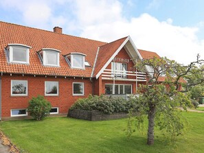 A red brick house with a sloped roof, multiple windows, and a well-maintained lawn. - 40 Person Holiday Home in Hurup Thy (Hurup Thy)