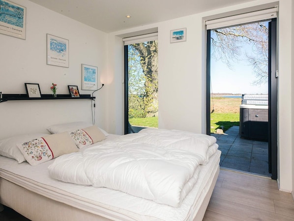 Ein Schlafzimmer mit einem Bett, einem Fenster und Blick auf einen Garten.
