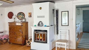A cozy living room with a fireplace, wooden furniture, and decorative items. - Holiday Home in Gedser (Gamleby)