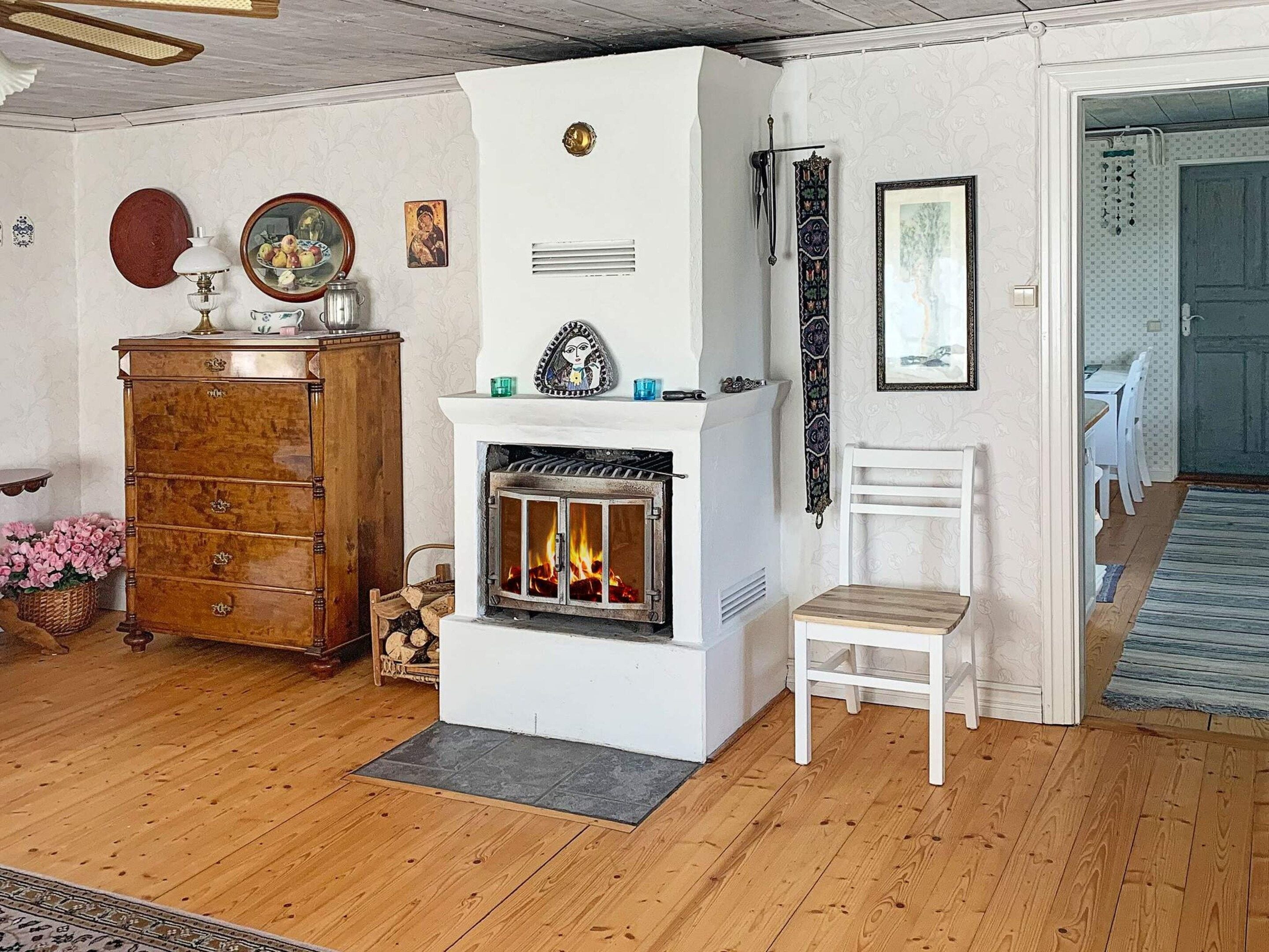 A room with a fireplace, wooden furniture, and a white chair.