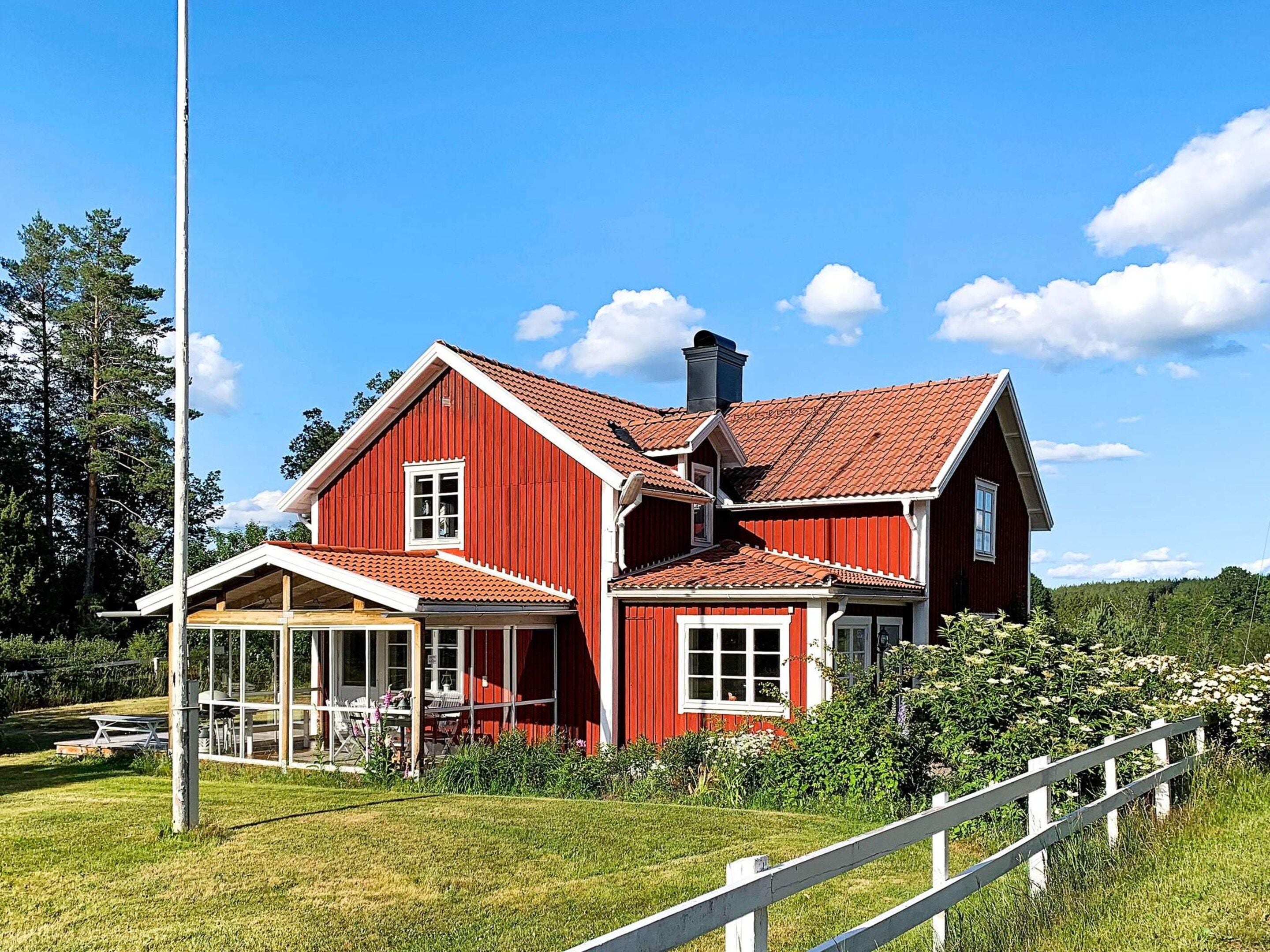 A red wooden house with a large porch and a chimney.