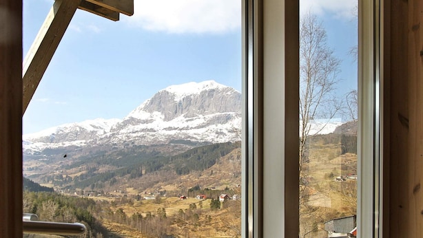 A mountain view from a window with a wooden interior and a metal railing. - 10 Person Holiday Home in Bygstad (Sunnfjord)